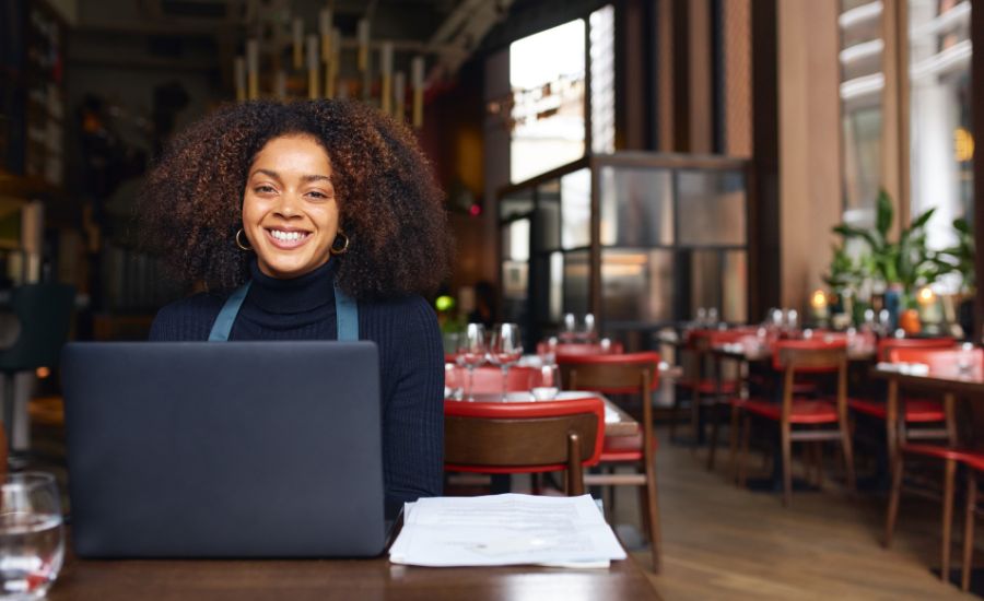 Restaurant owner sitting at table on laptop