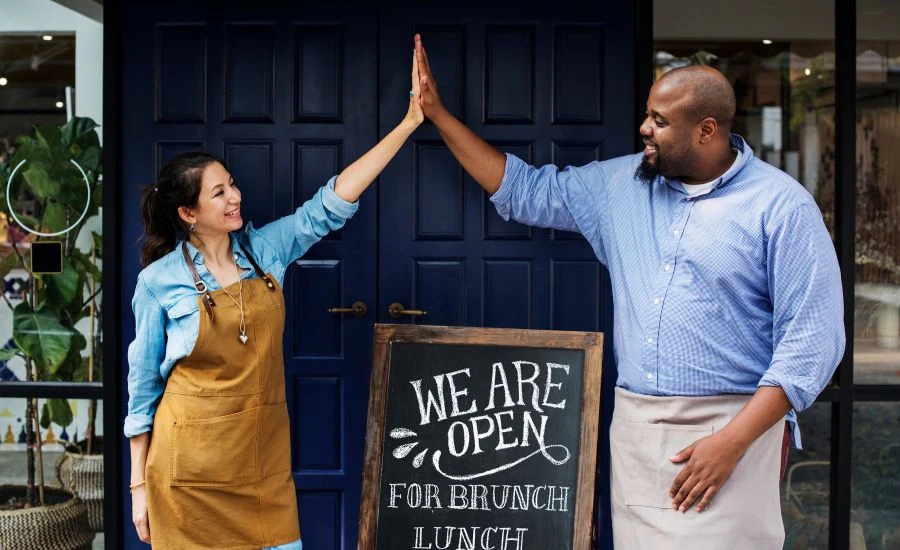 small business owners high-five over open sign