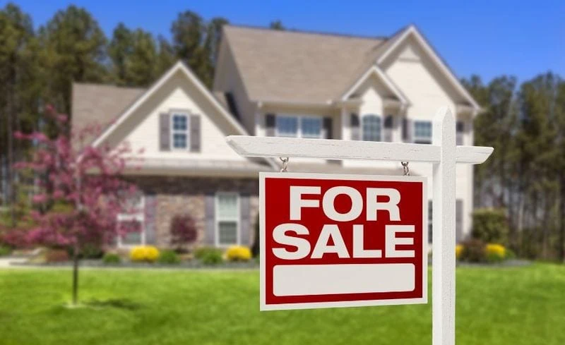 Photo of a house with a for sale sign in front of it