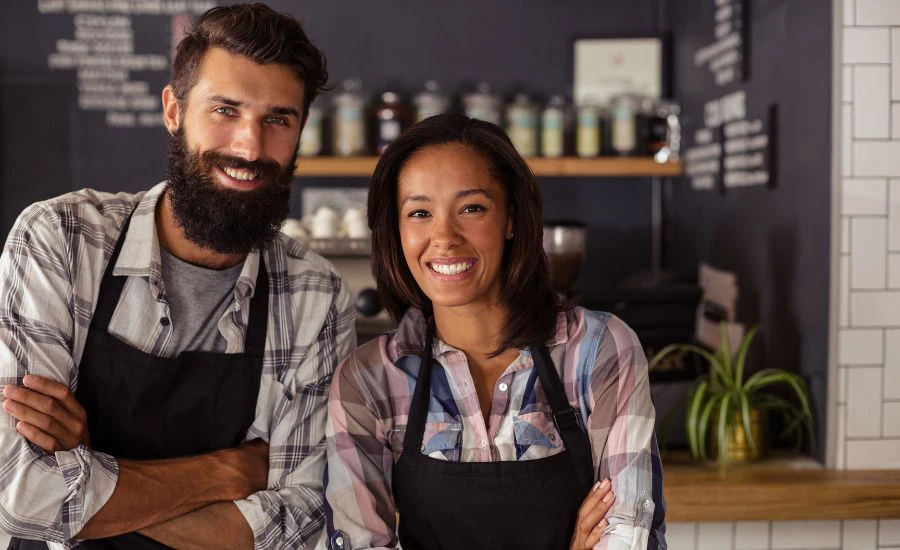 Store owners smiling with arms crossed inside of the business