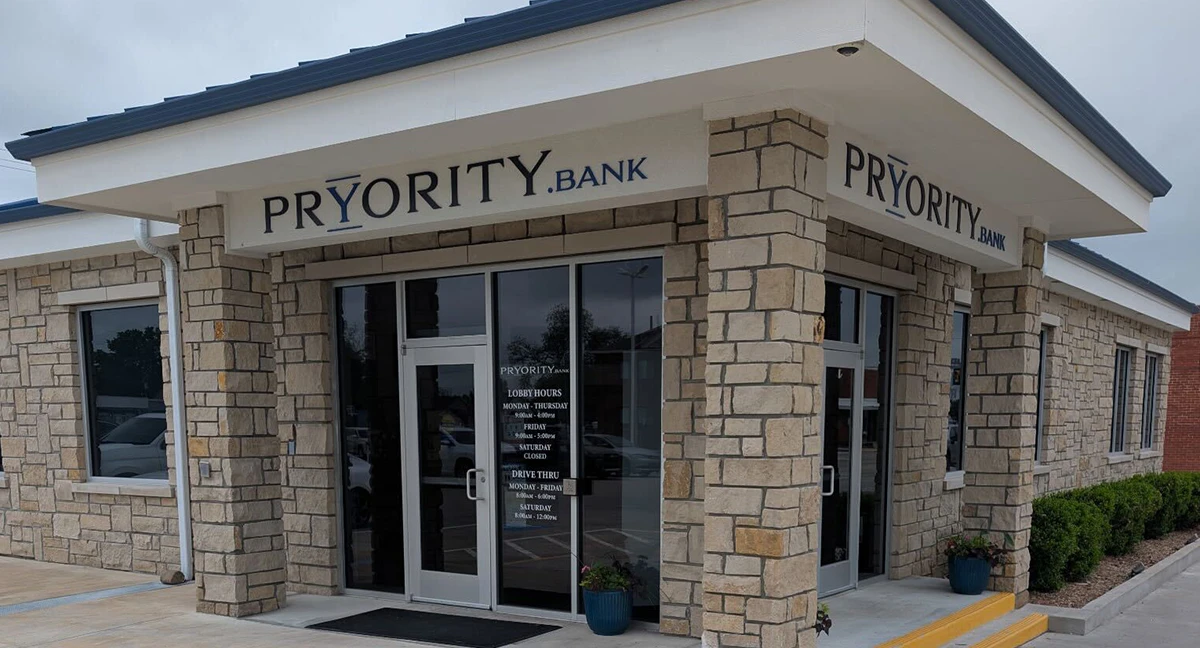 Stone columns around a glass door with the name Pryority Bank above the entrance.